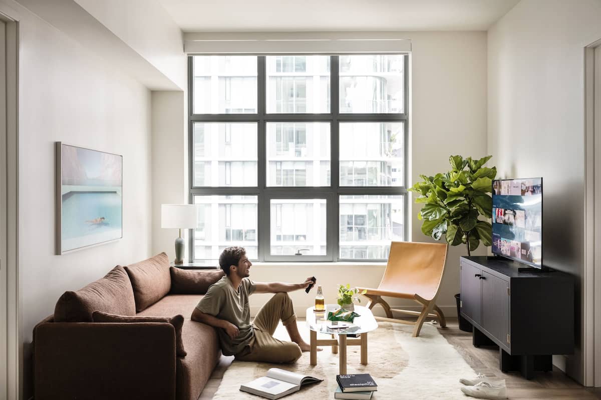 A modern living room with a large window, a sofa, a coffee table, a TV, and a bookshelf.