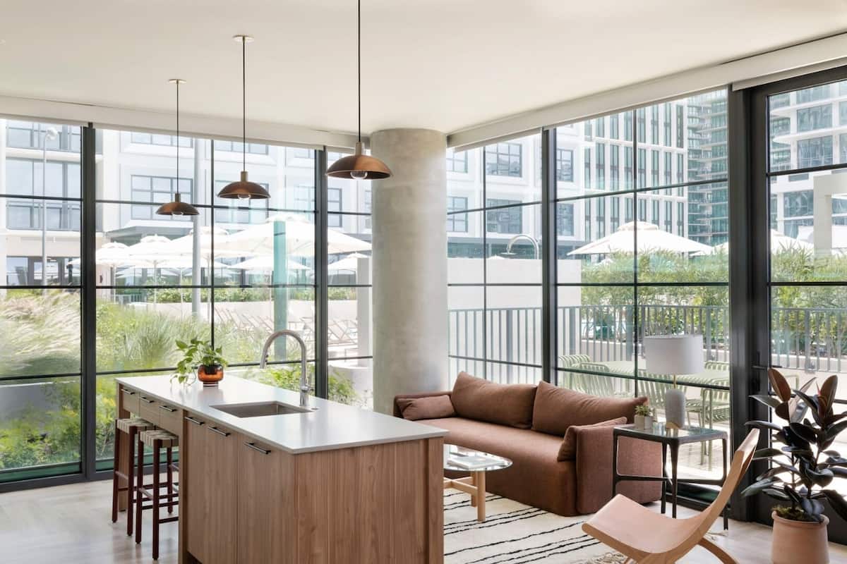 A modern kitchen with a central island, bar stools, and a seating area with a sofa and chairs.