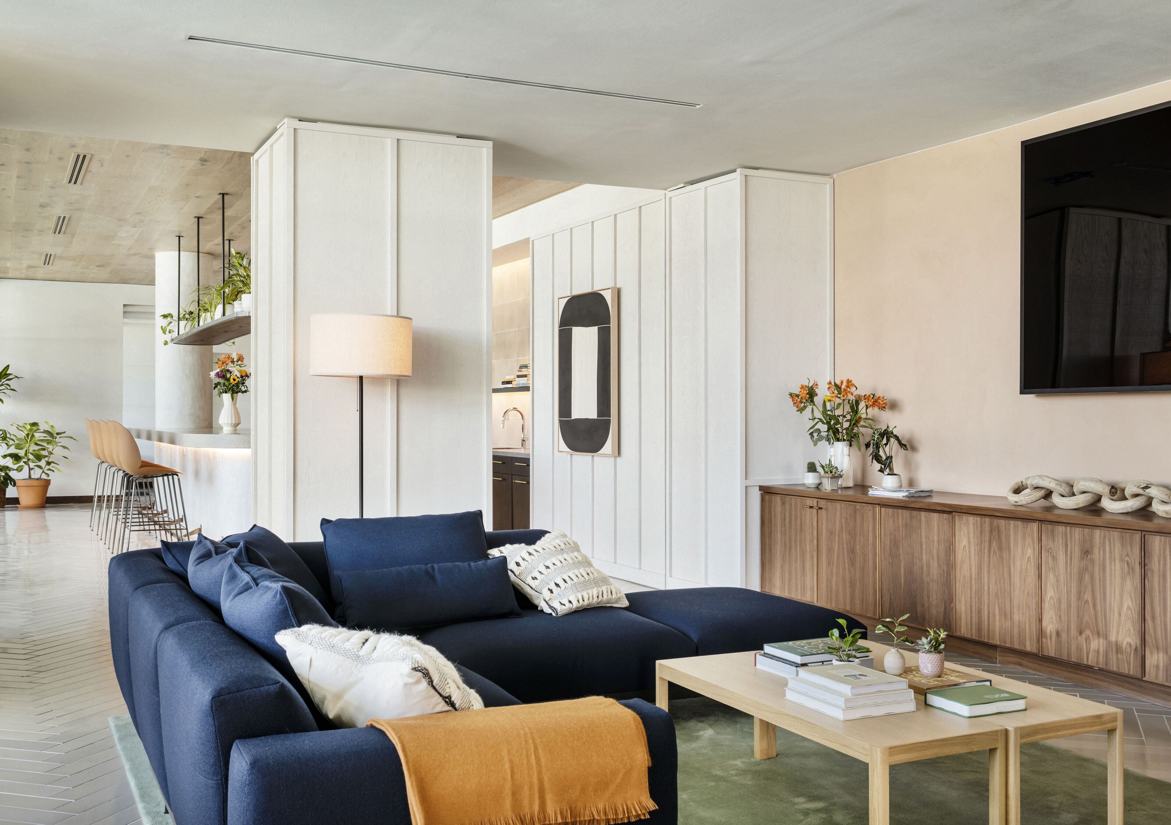 Una sala de estar moderna con un sofá azul oscuro, una mesa de centro de madera y una separador blanco.