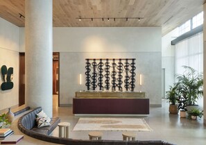 A modern lobby with a curved sofa, a central console table, and a decorative wall piece.