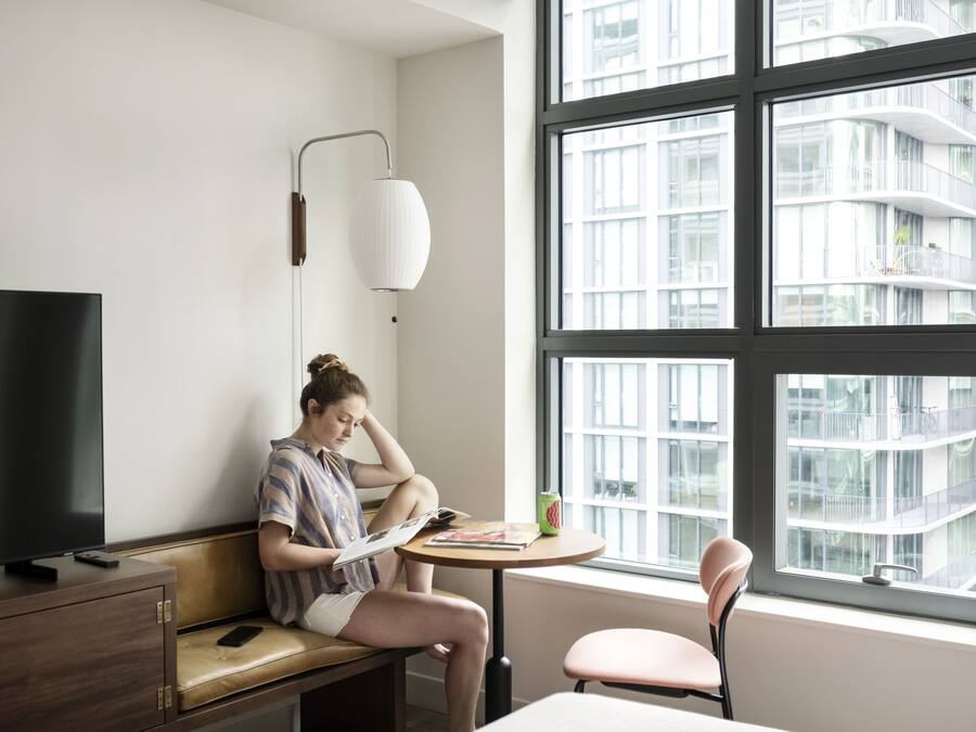 Ein modernes Zimmer mit einem großen Fenster, einem Fernseher, einem Schreibtisch und einem Stuhl.