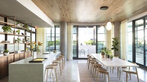 A modern kitchen with a large island, wooden cabinets, and ample natural light from large windows. - ROOST Tampa (Tampa)