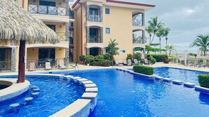 Un hôtel doté d’une piscine, d’un espace extérieur aménagé et de palmiers.