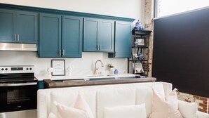 A modern kitchen with teal cabinets, a white countertop, and a built-in oven. - Luxury loft in historic downtown Tifton, Georgia (Tifton)