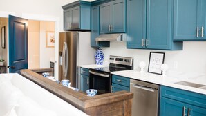 A modern kitchen with teal cabinets, stainless steel appliances, and a wooden countertop. - Luxury loft in historic downtown Tifton, Georgia (Tifton)