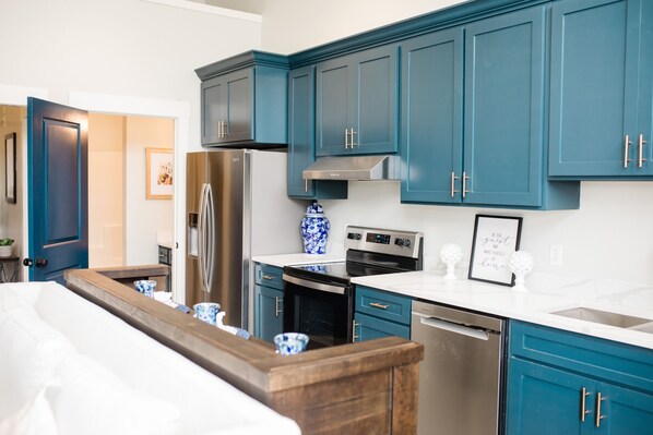 A modern kitchen with teal cabinets, stainless steel appliances, and a wooden countertop. - Luxury loft in historic downtown Tifton, Georgia (Tifton)