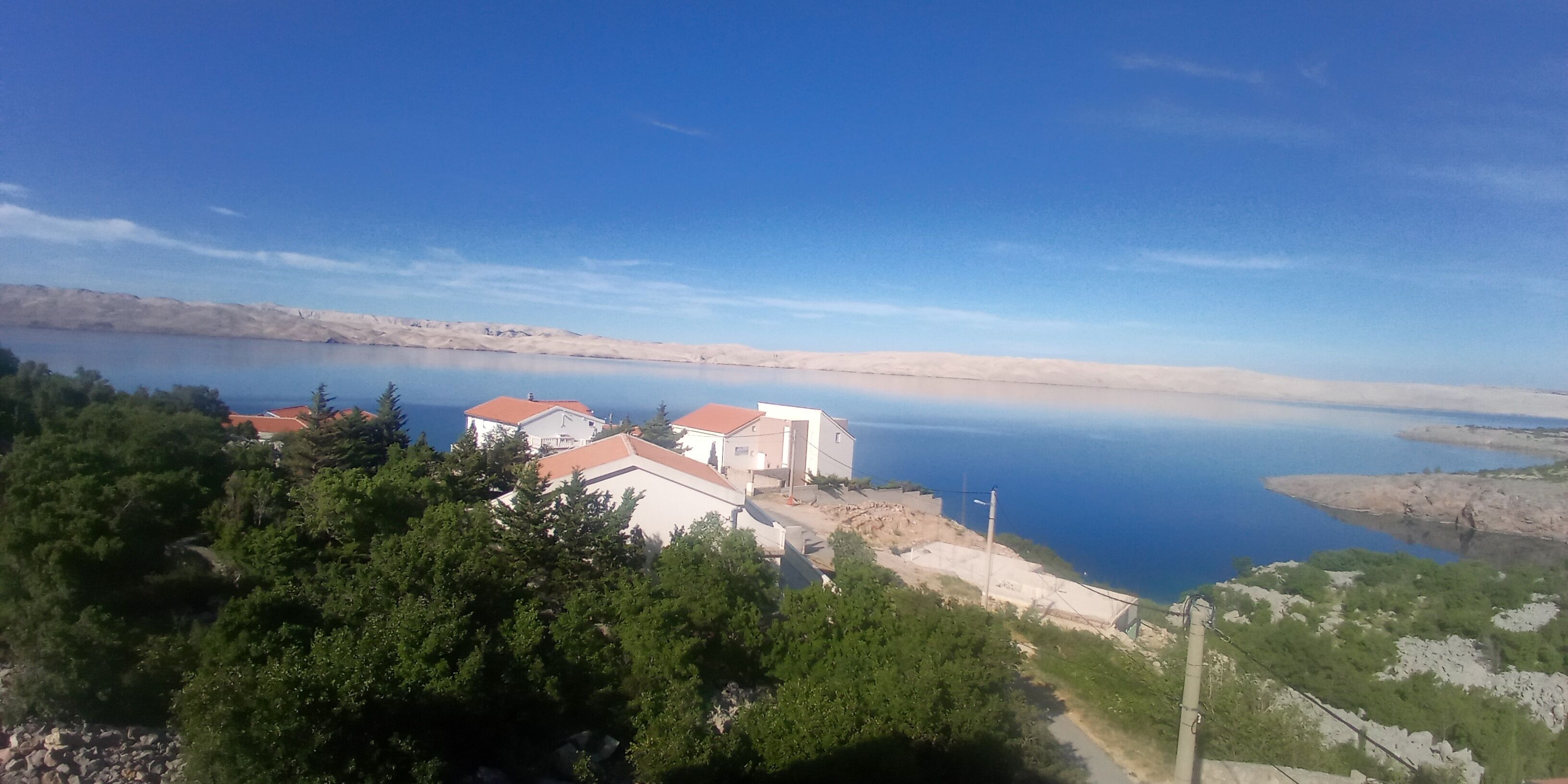A coastal area with buildings, trees, and a calm body of water.
