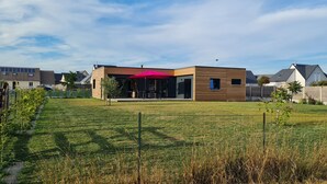 A modern house with a patio and a fenced yard. - Bright new wooden house with enclosed garden 5 minutes from the beach (Gouville-sur-Mer)