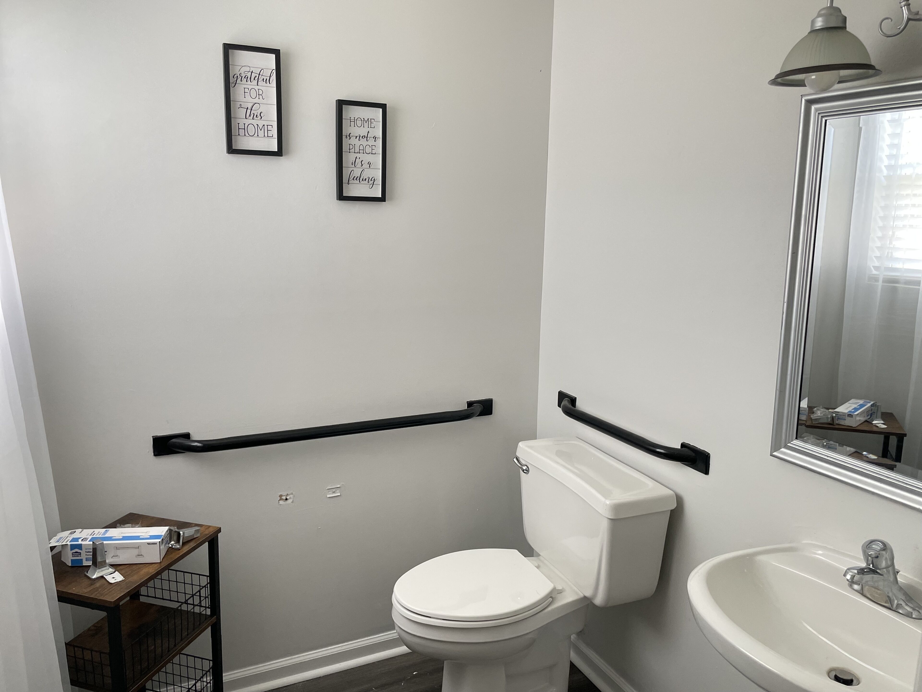 A bathroom with a toilet, a sink, and two framed quotes on the wall.
