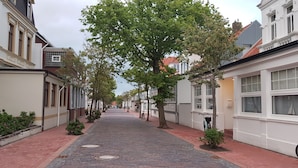 A cobblestone street lined with historic buildings, trees, and a bicycle. - Cozy, quiet and central, a few meters to the beach, swimming pool in the house (Norderney)