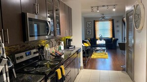 A modern kitchen with dark cabinets, stainless steel appliances, and a central island. - High Rise Condo/Apartment in the Medical Center Area (Houston)