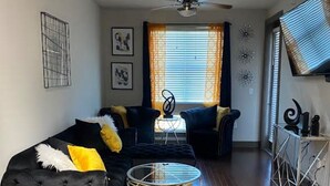 A modern living room with a sofa, a coffee table, and a TV on a stand. - High Rise Condo/Apartment in the Medical Center Area (Houston)