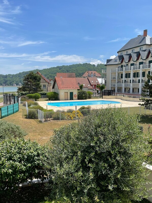 A pool area with a view of a building with multiple balconies and a red-roofed structure.