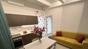 Une cuisine moderne avec un coin repas, un canapé jaune et un vase rempli de fleurs sur la table.