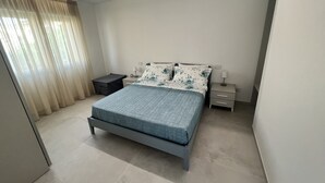 Une chambre à coucher avec un lit, des tables de chevet, une commode et une fenêtre avec des rideaux.