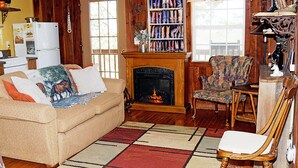 Un salon chaleureux avec une cheminée, un canapé agrémenté de coussins décoratifs, un tapis à motifs et un fauteuil.