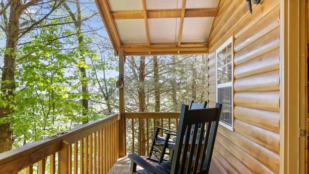 Une cabane en bois avec une véranda, une chaise berçante et une fenêtre.