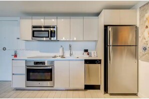 Fully equipped kitchen with stainless steel appliances, white cabinetry, and a dishwasher.
