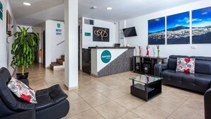 Een hotel receptie met een receptiebalie, een bank, een salontafel en een grote kamerplant.