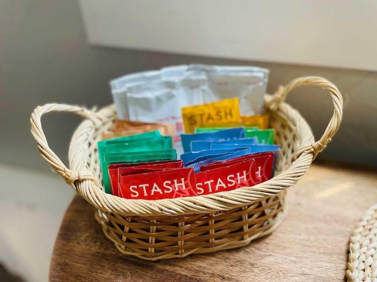 En fletkurv med farverige plastikposer mærket "STASH" på en træoverflade.