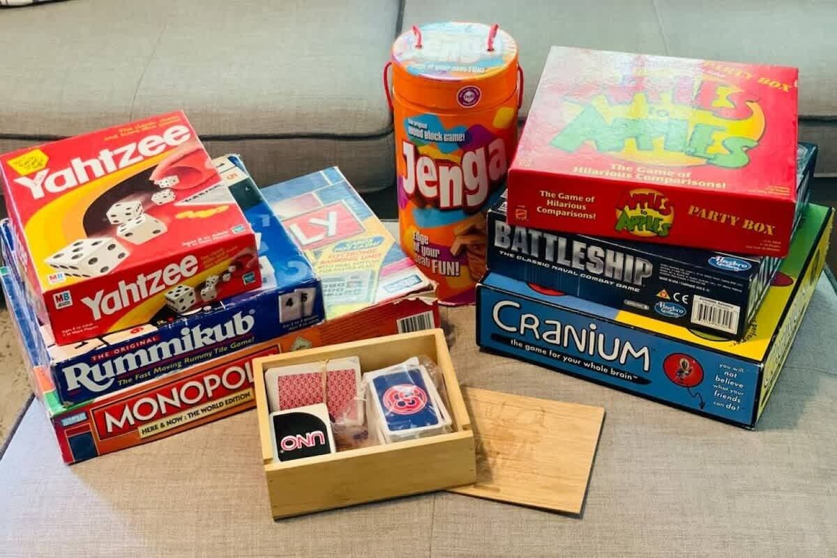 Verschiedene Brettspiele, darunter Yahtzee, Jenga und Monopoly, zusammen mit einer Holzkiste und einigen Karten.