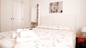 A bedroom with a large bed, a wardrobe, a mirror, and a wall-mounted artwork. - Centrally located on the beachfront in Los Cristianos (Arona)