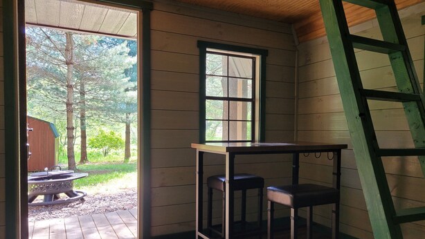 Una habitación con paredes de madera, una ventana, una mesa y dos taburetes.