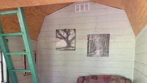 Acogedor cuarto ático con una escalera de madera, un sofá estampado y dos cuadros en la pared.