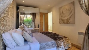 Un dormitorio con una cama grande, un armario, un espejo y una obra de arte en la pared.