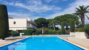 Una piscina con agua cristalina azul, rodeada por un jardín bien cuidado con diversas plantas y árboles.