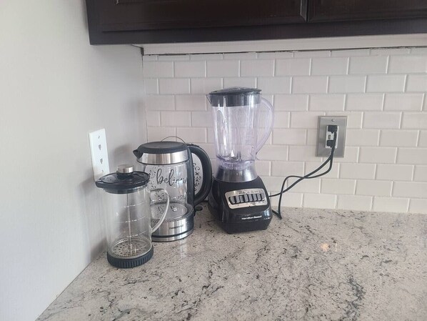 A kitchen with a blender, a coffee maker, and a glass carafe on a granite countertop. - Lochsa fun in new Meridian (W/D and King Bed) (Meridian)