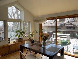 A dining area with a wooden table, chairs, and a vase of flowers. There are large windows and a view of the outside. - Best Neighborhood in Boulder (Boulder)