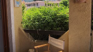 A small balcony with a wooden chair, a woven mat, and a decorative wall piece. - Casa Maria Pia, relaxation and sea in the heart of Cannigione (Cannigione)