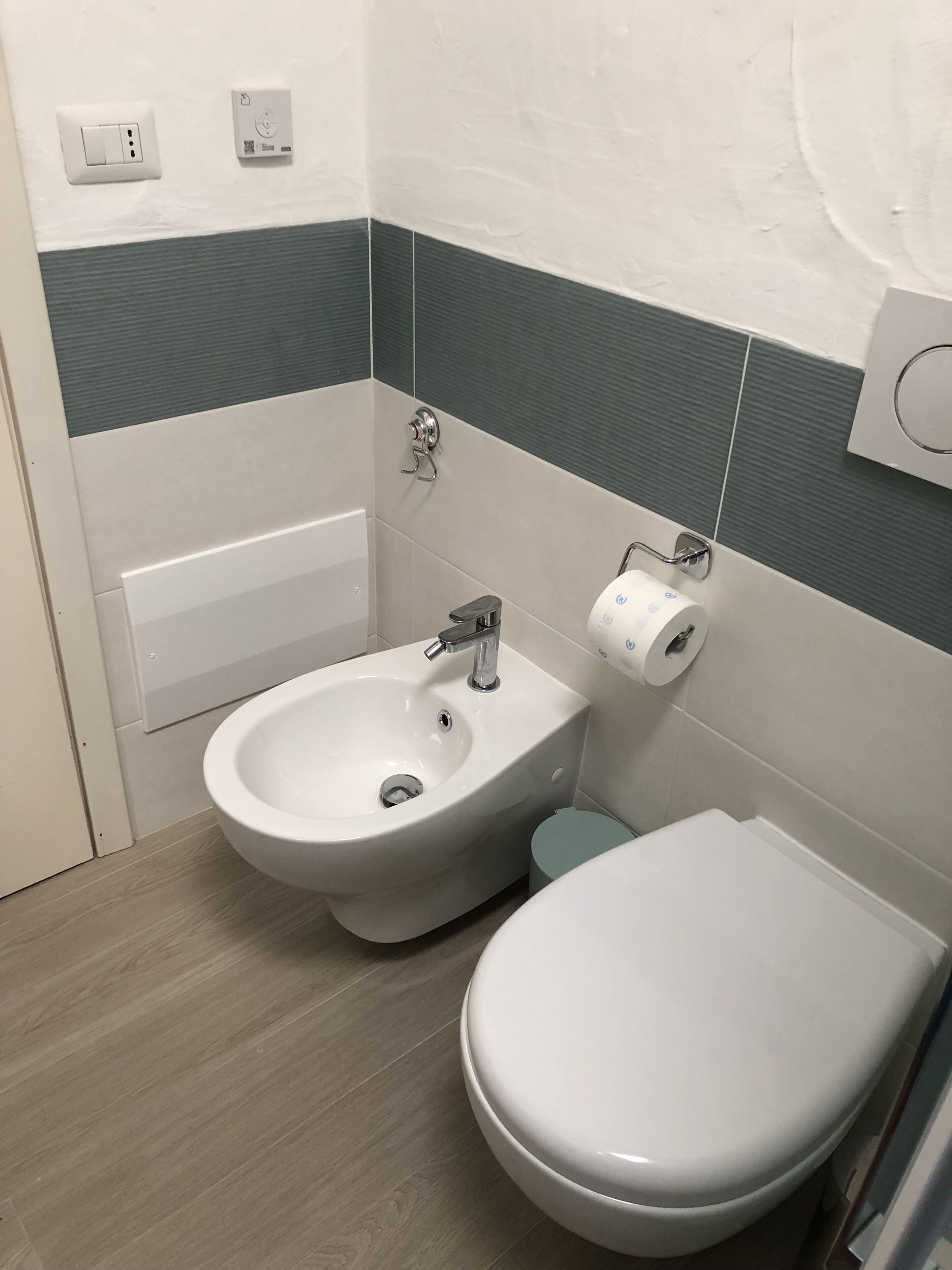 Une salle de bain équipée d’un bidet, de toilettes et d’un lavabo fixé au mur.