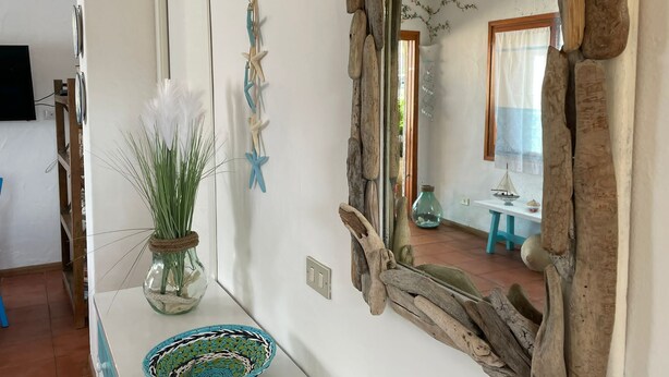 A room with a rustic mirror, a vase with green plants, and a woven bowl on a white counter. - Casa Maria Pia, relaxation and sea in the heart of Cannigione (Cannigione)