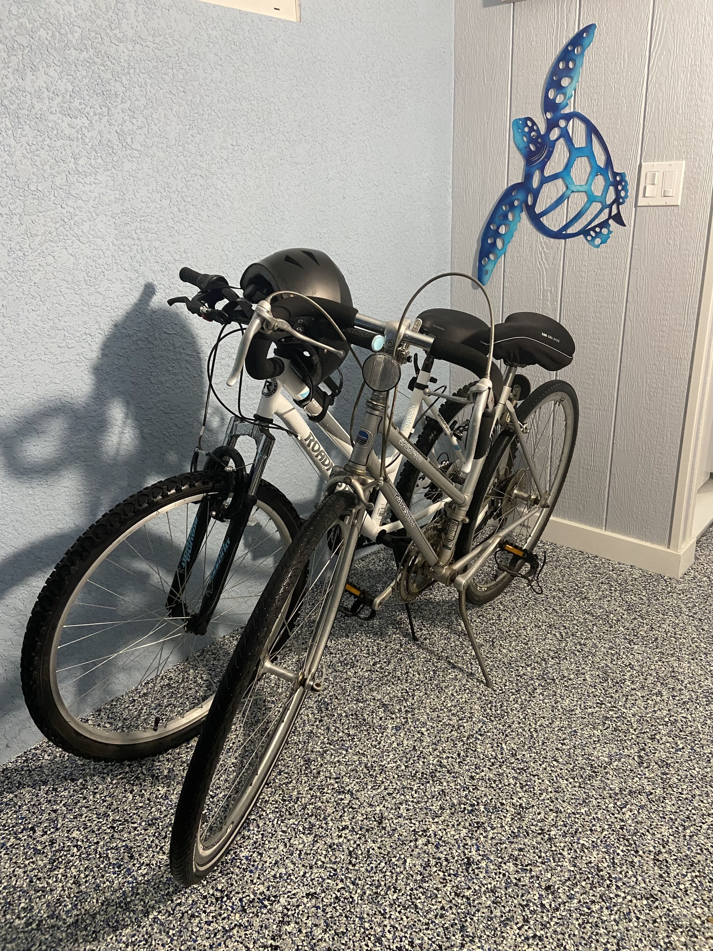 Una bicicleta estacionada en el interior, junto a una pared con textura y una decoración de tortuga azul.