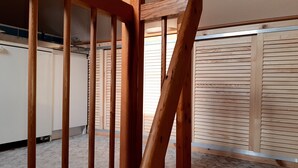 Een kamer met een houten trap, een inloopkast met schuifdeuren en een vloerkleed.