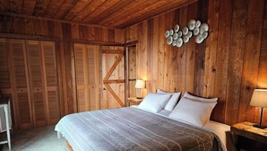 Una stanza in legno con un letto, un comodino e una lampada a parete.