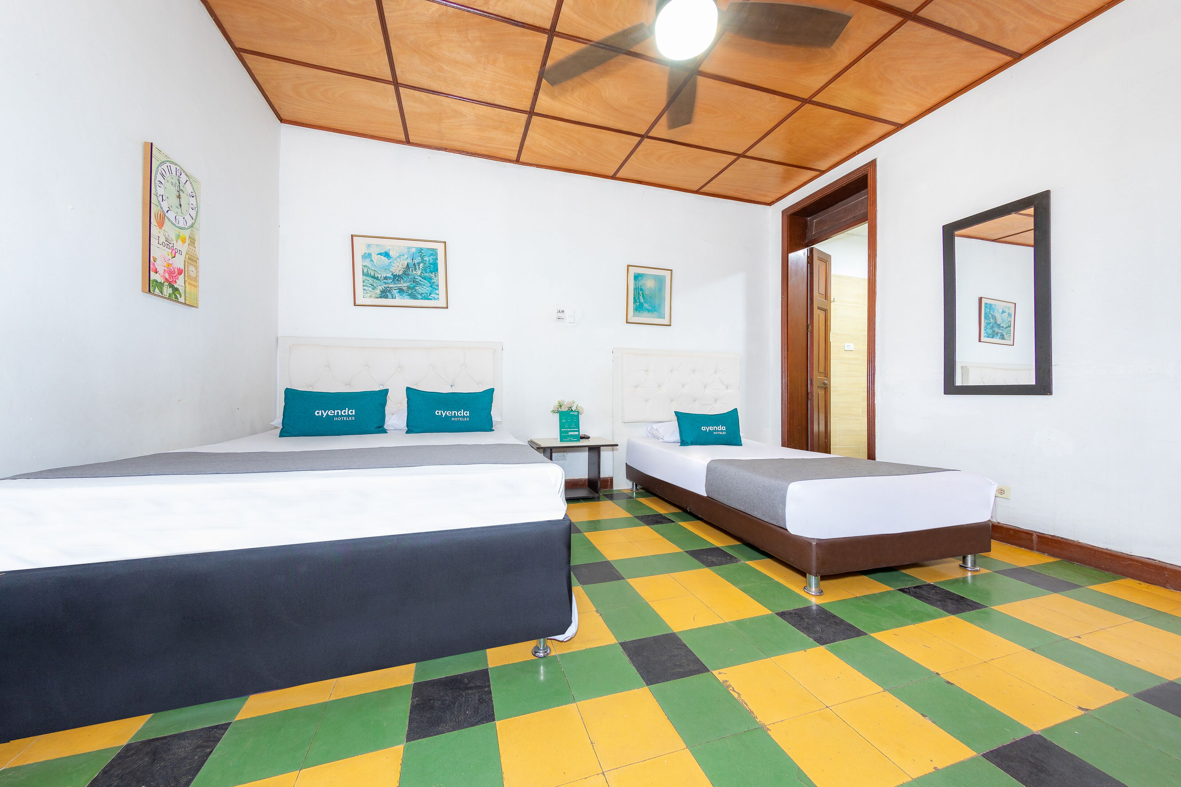 A hotel room with two beds, a ceiling fan, and a checkered floor.