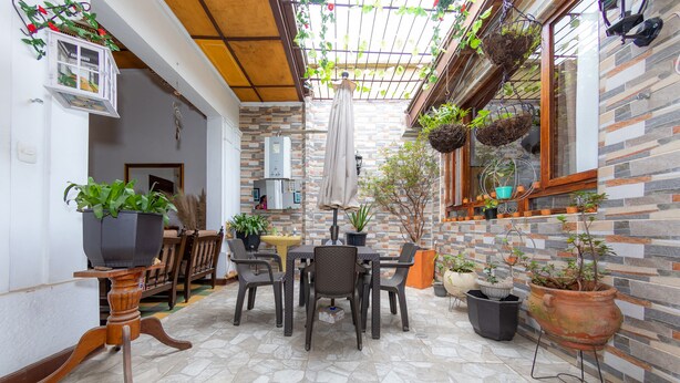 Eine Terrasse mit Tisch und Stühlen, umgeben von Kübelpflanzen und einer Backsteinmauer.