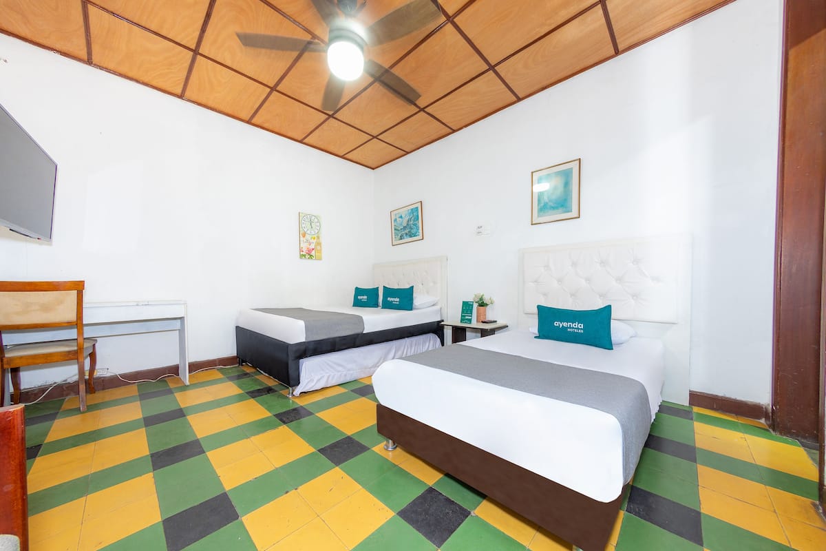 Una habitación de hotel con una cama grande, una cama más pequeña, un escritorio y una silla.