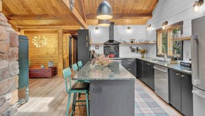 A modern kitchen with a large island, wooden ceiling beams, and stainless steel appliances. - Sky Pine Lodge - Chalet Atop the World (Jim Thorpe)