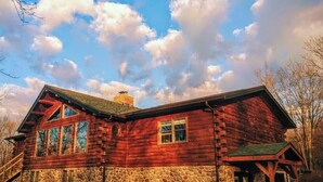 A log cabin with a stone foundation, large windows, and a chimney. - Sky Pine Lodge - Chalet Atop the World (Jim Thorpe)