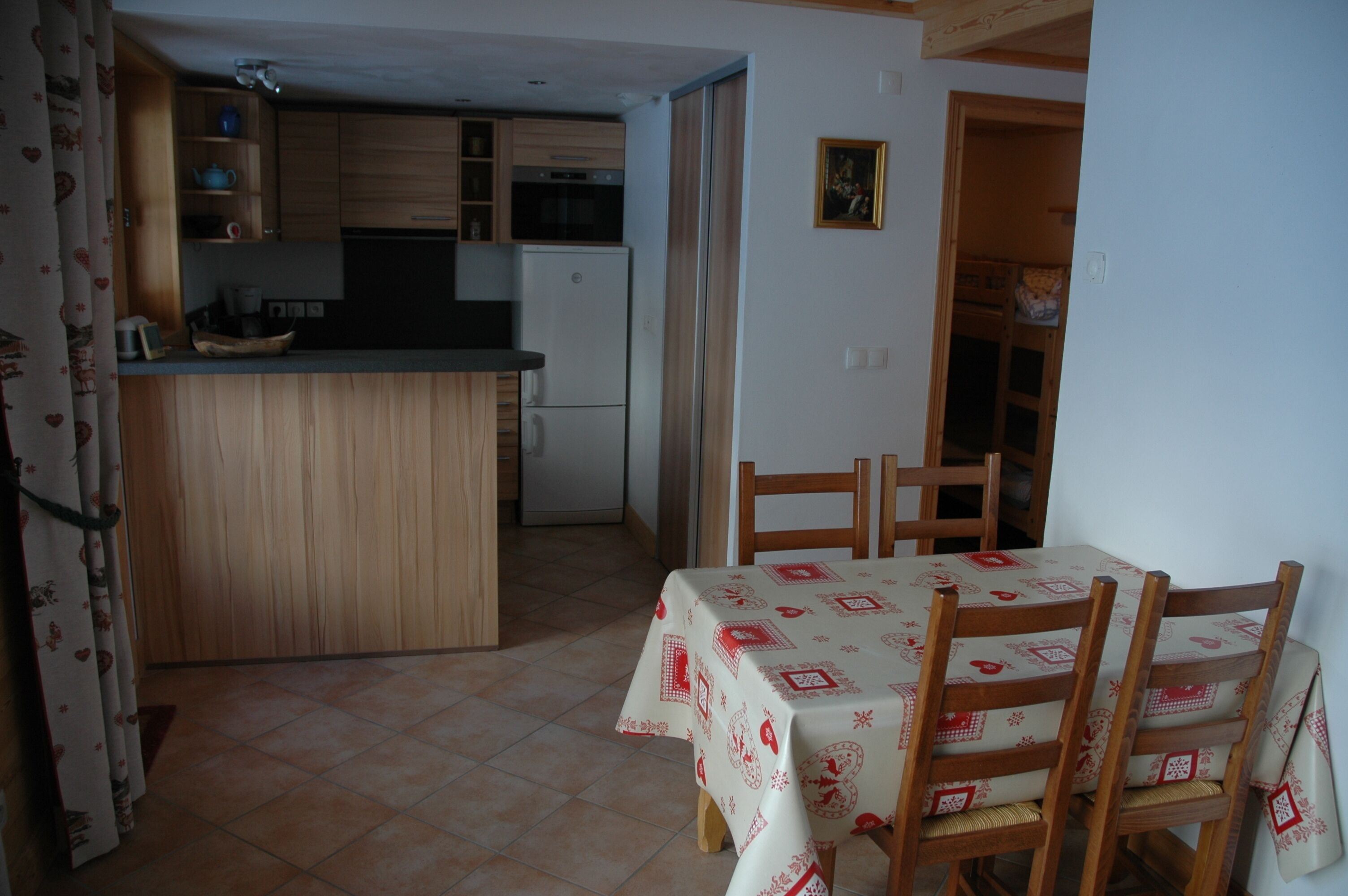 A compact kitchen with a central island, wooden cabinets, and a dining area with a table and chairs.
