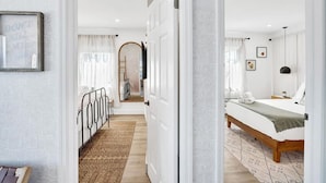 A hotel room with a bed, bedside table, and a view of the hallway. - Casa De Amigos | Private Pool | Outdoor Oasis (Fort Lauderdale)