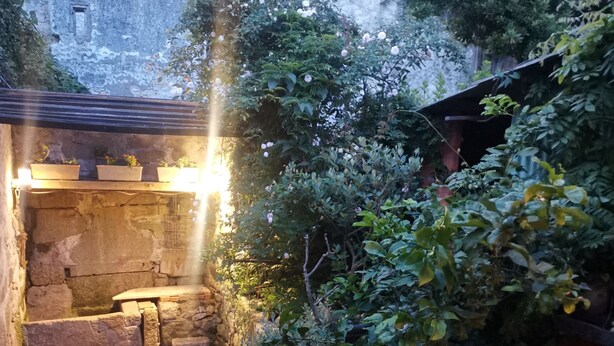 A stone courtyard with a bench, potted plants, and a small table. - Porto Old Downtown - Vérités Dame (Porto)