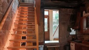 A rustic kitchen with wooden stairs leading to a loft area, a small sink, and a window providing natural light. - Porto Old Downtown - Vérités Dame (Porto)