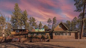 A wooden cabin with a sign reading "Creekside Cabins & Tavern" and a sign indicating breakfast service. - Forest Cabin 6 Enchanted Forest (Payson)