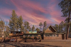 A wooden cabin with a sign reading "Creekside Cabins & Tavern" and a sign indicating breakfast service.