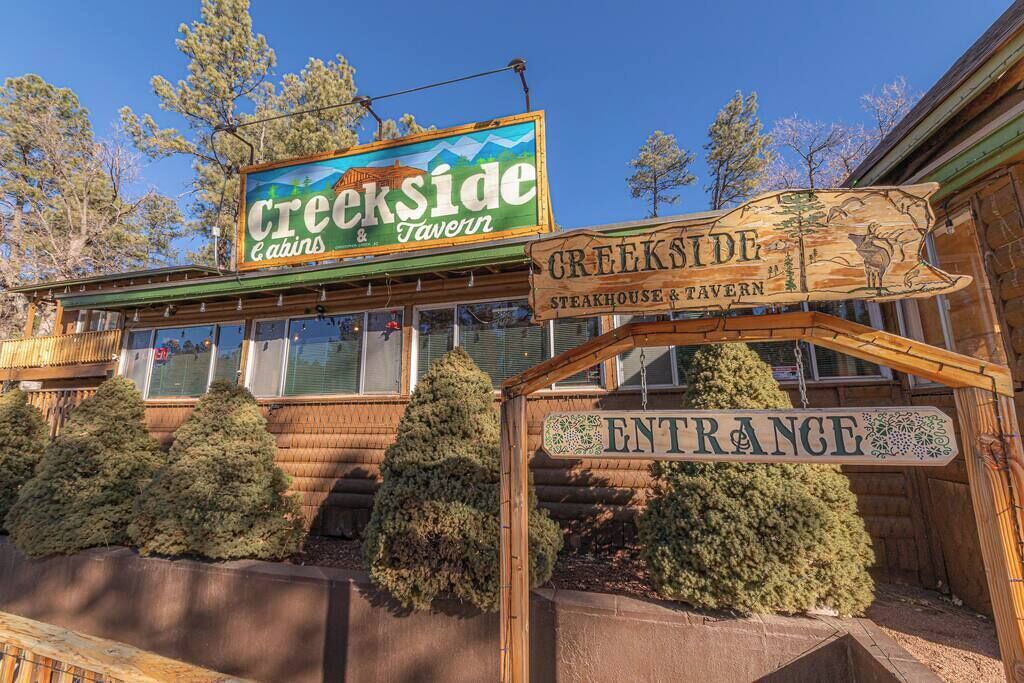 Edifici de fusta amb un cartell que diu "Creekside Cabins & Tavern" i un altre cartell per a "Creekside Steakhouse & Tavern".